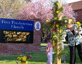 Children help place flowers on the cross